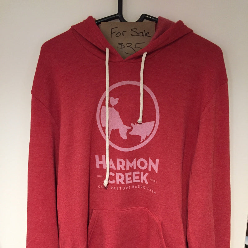 A red hoodie with a graphic print of an animal and the text 'HARMON CREEK', displayed on a hanger.