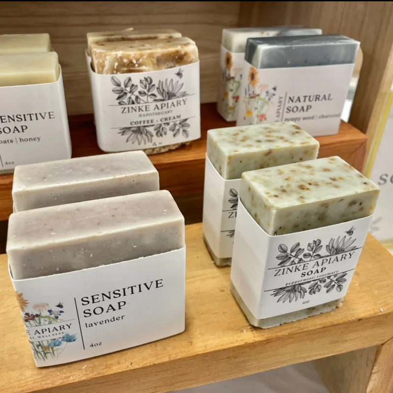 A variety of soap bars on display, each with different labels indicating various natural ingredients such as sensitive soap, honey, and peppermint.